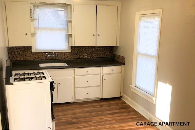 kitchen with tasteful backsplash, gas range oven, sink, and white cabinets