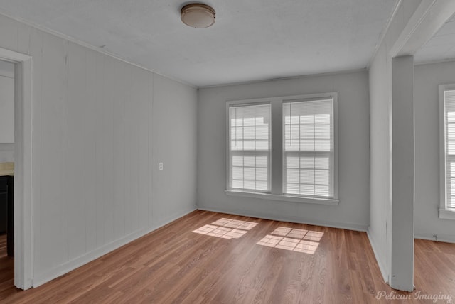 unfurnished room featuring crown molding, plenty of natural light, and light hardwood / wood-style flooring