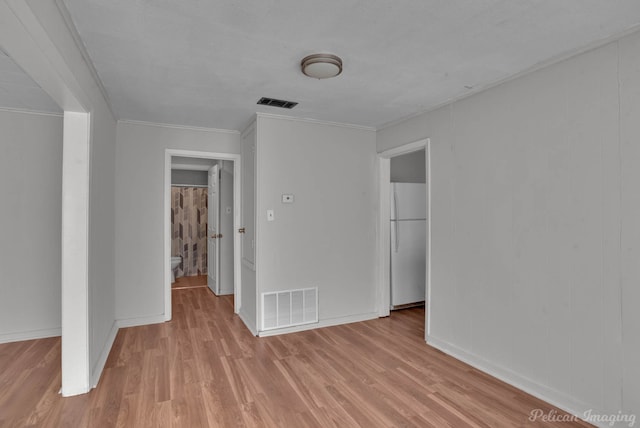 unfurnished bedroom featuring ornamental molding, white fridge, and light hardwood / wood-style floors