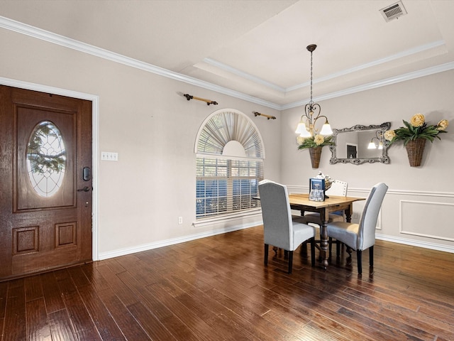 dining room with a raised ceiling, dark hardwood / wood-style flooring, ornamental molding, and a notable chandelier