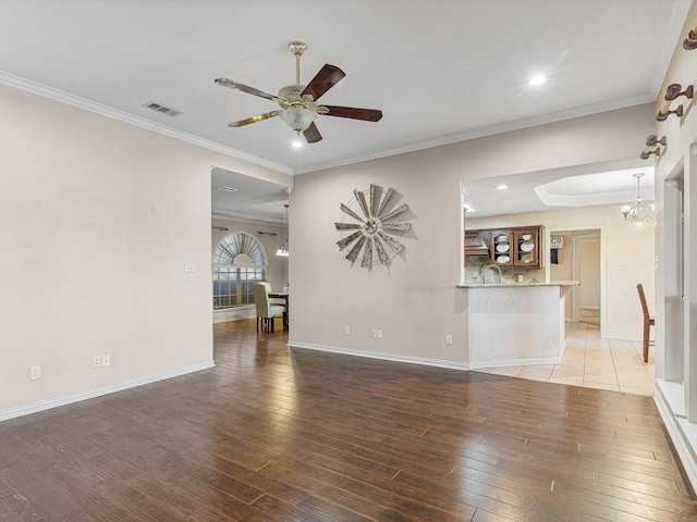 spare room featuring ceiling fan with notable chandelier, dark hardwood / wood-style flooring, and ornamental molding