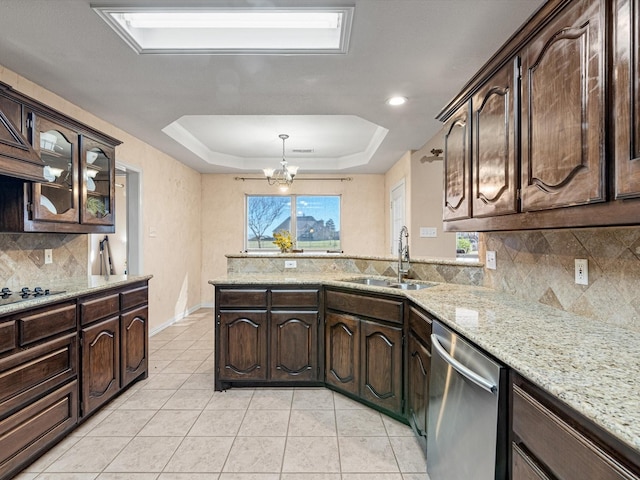 kitchen featuring a raised ceiling, dark brown cabinetry, sink, and stainless steel dishwasher