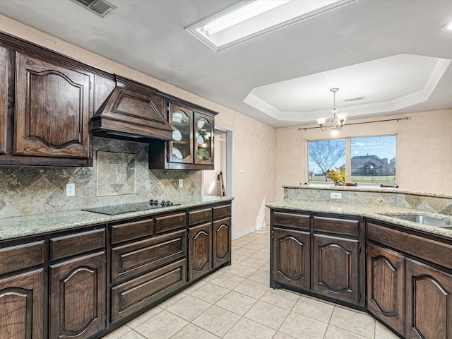 kitchen with dark brown cabinets, black electric cooktop, a chandelier, and a tray ceiling