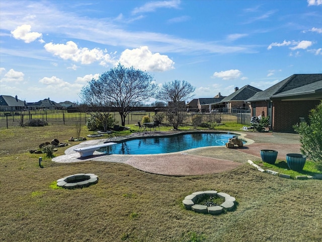 view of swimming pool featuring a fire pit, a diving board, a patio area, and a yard