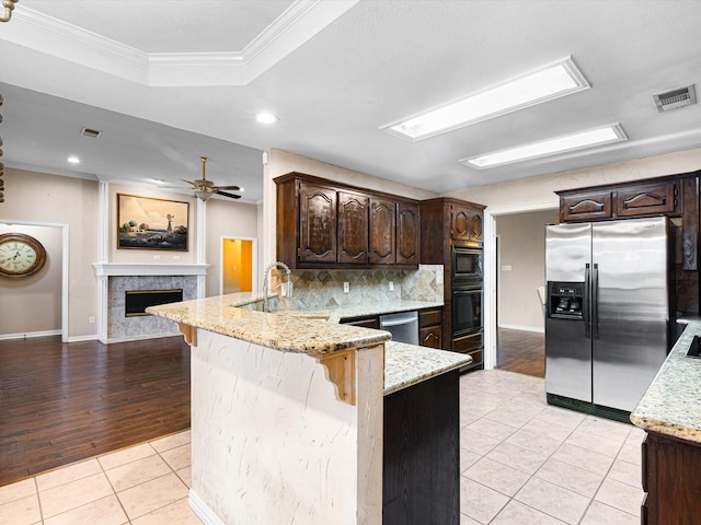 kitchen with kitchen peninsula, stainless steel appliances, crown molding, sink, and light tile patterned floors