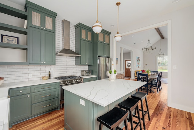 kitchen featuring pendant lighting, a center island, wall chimney exhaust hood, vaulted ceiling with beams, and appliances with stainless steel finishes