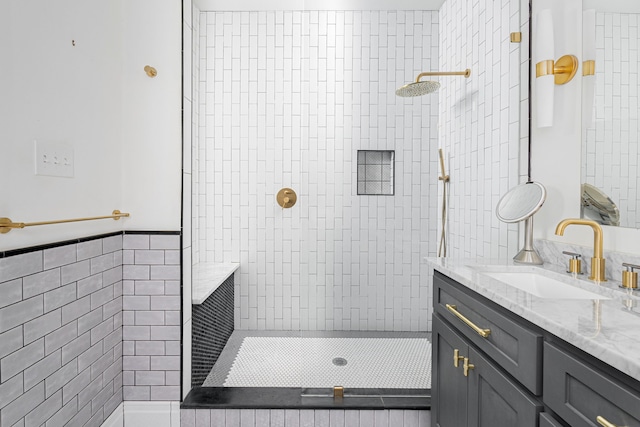 bathroom with tiled shower, vanity, and tile walls