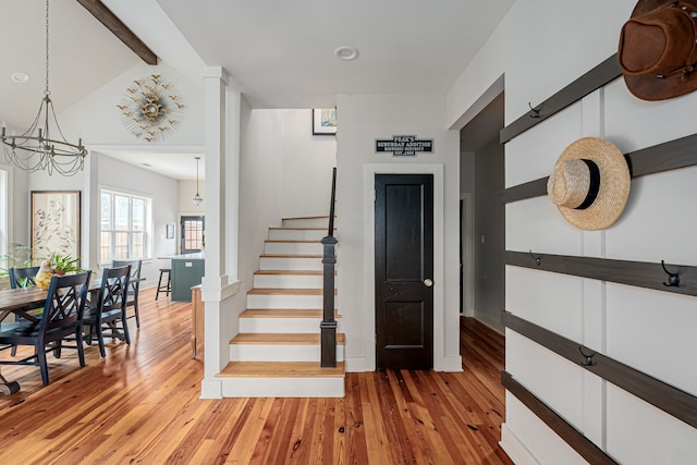 stairway featuring vaulted ceiling with beams, hardwood / wood-style flooring, and a notable chandelier