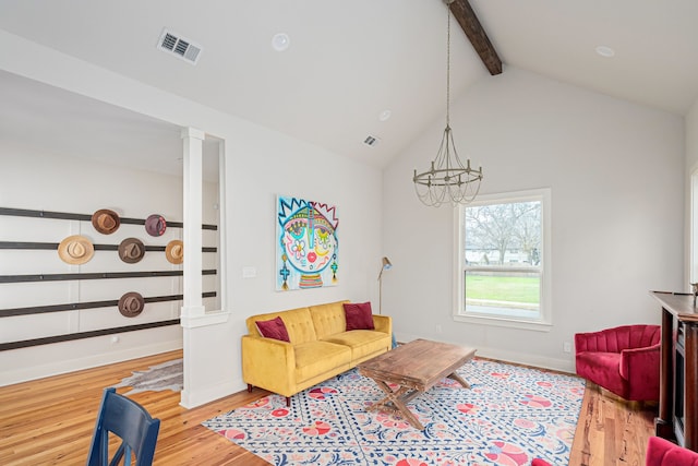 living room with ornate columns, a chandelier, light hardwood / wood-style floors, and vaulted ceiling with beams