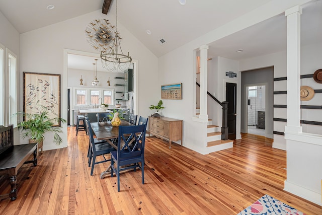 dining area featuring vaulted ceiling with beams, a notable chandelier, ornate columns, and light hardwood / wood-style flooring