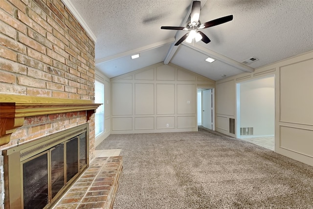 unfurnished living room featuring vaulted ceiling with beams, ceiling fan, a textured ceiling, a fireplace, and light colored carpet