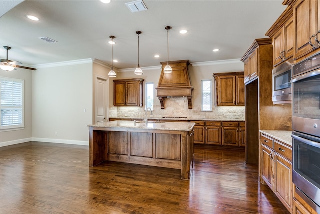 kitchen featuring sink, dark wood-type flooring, light stone counters, an island with sink, and pendant lighting