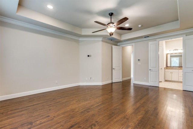 unfurnished bedroom with a tray ceiling, connected bathroom, ceiling fan, and crown molding