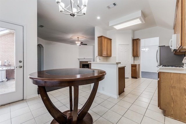 kitchen featuring ceiling fan with notable chandelier, kitchen peninsula, hanging light fixtures, and light tile patterned floors