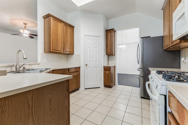 kitchen with ceiling fan with notable chandelier, white appliances, sink, light tile patterned floors, and hanging light fixtures