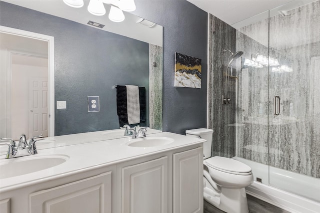 bathroom featuring vanity, hardwood / wood-style flooring, toilet, and a shower with door