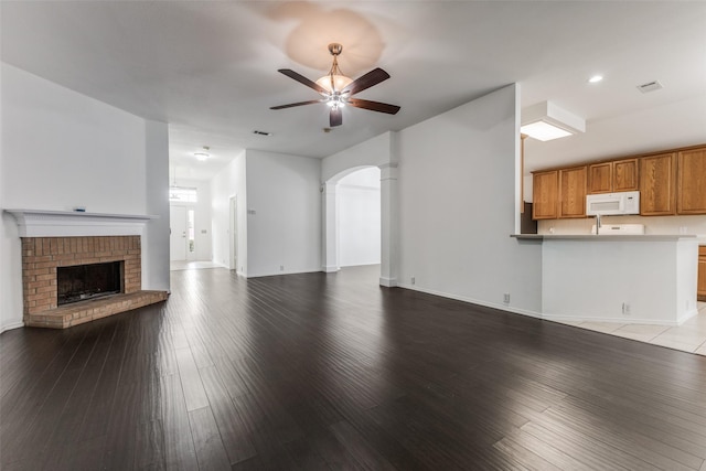 unfurnished living room featuring a fireplace, light wood-type flooring, and ceiling fan