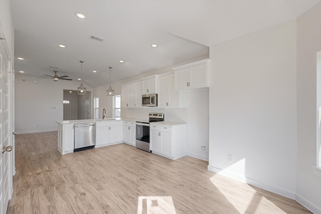 kitchen with kitchen peninsula, appliances with stainless steel finishes, white cabinets, and sink