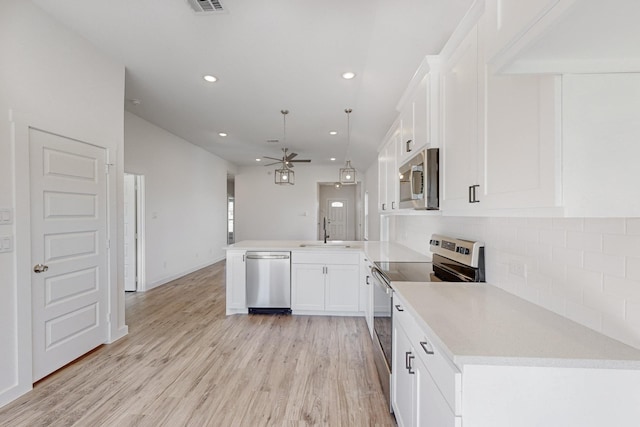 kitchen featuring white cabinets, sink, appliances with stainless steel finishes, decorative light fixtures, and kitchen peninsula