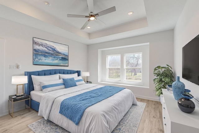 bedroom featuring a tray ceiling, ceiling fan, and light hardwood / wood-style flooring