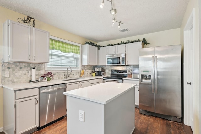 kitchen with white cabinetry, sink, a center island, a textured ceiling, and appliances with stainless steel finishes