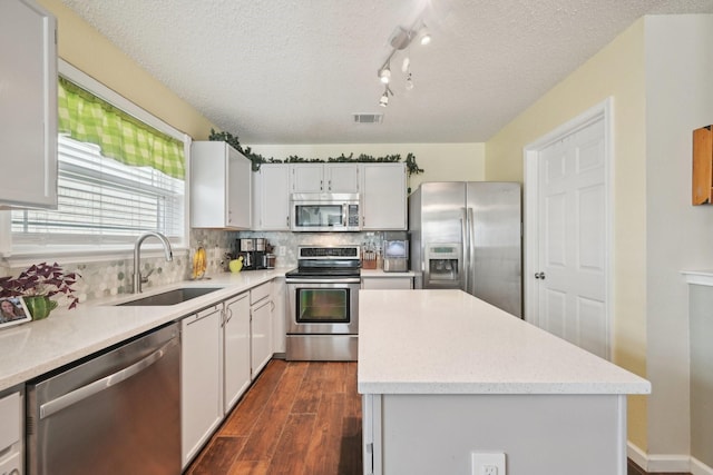 kitchen featuring a textured ceiling, a kitchen island, sink, and appliances with stainless steel finishes