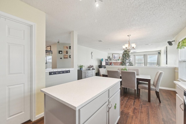 kitchen with hanging light fixtures, a kitchen island, dark hardwood / wood-style flooring, a chandelier, and white cabinets