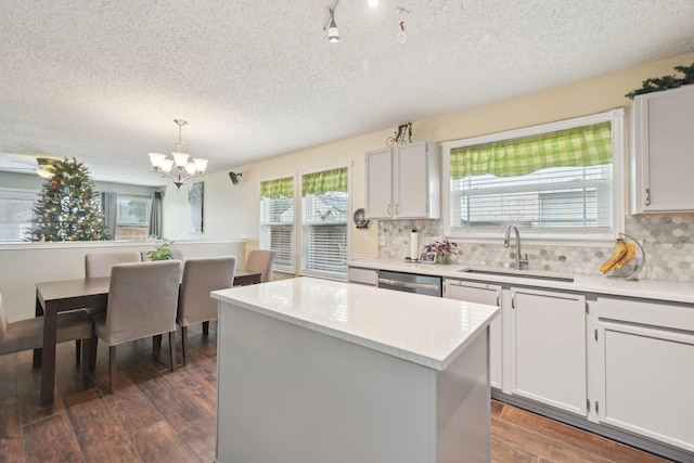 kitchen featuring a center island, dishwasher, sink, decorative light fixtures, and white cabinets