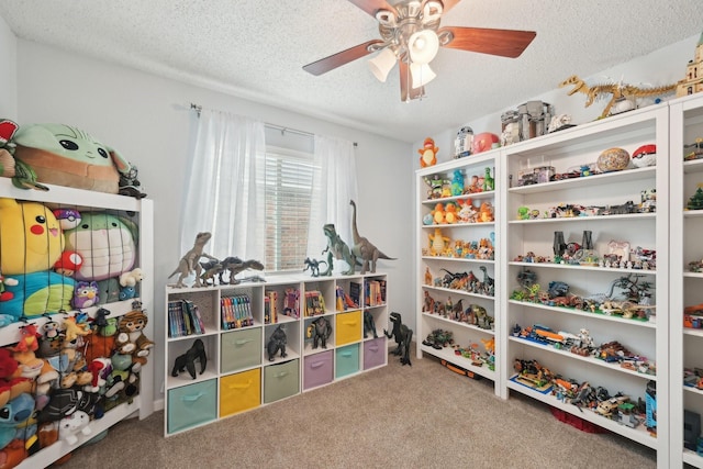 recreation room with carpet, ceiling fan, and a textured ceiling