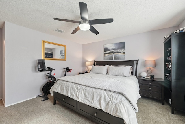 bedroom featuring a textured ceiling, light colored carpet, and ceiling fan