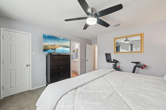 bedroom with carpet flooring, ensuite bath, ceiling fan, and a textured ceiling