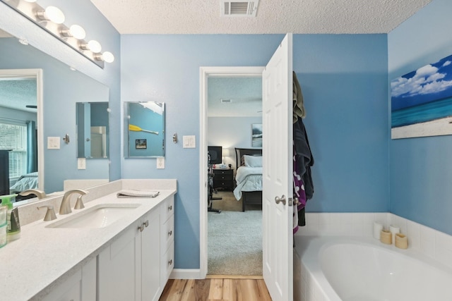 bathroom with vanity, hardwood / wood-style floors, a textured ceiling, and a bathtub