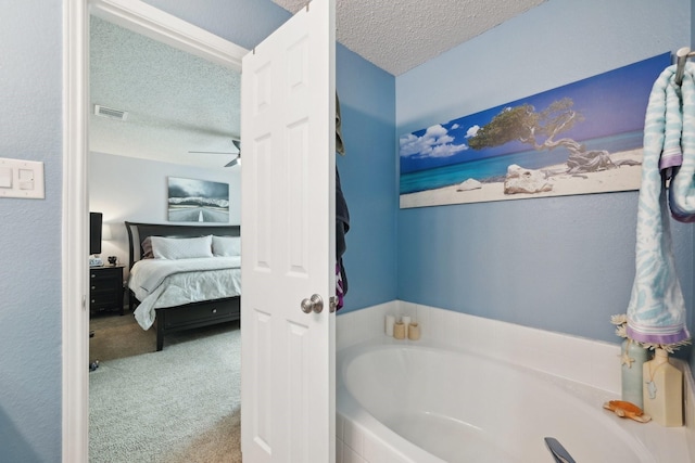 bathroom with ceiling fan, a tub to relax in, and a textured ceiling