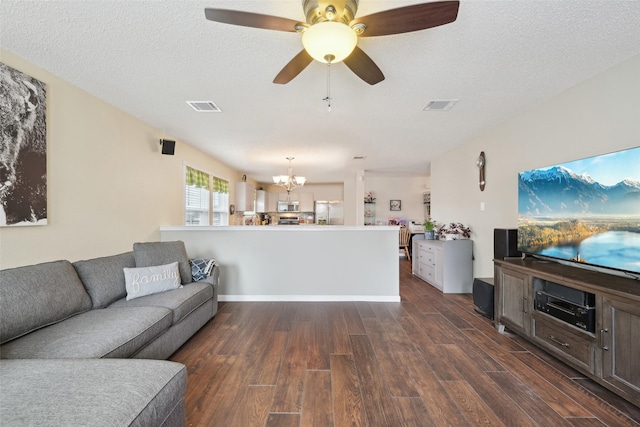 living room with a textured ceiling, dark hardwood / wood-style flooring, and ceiling fan with notable chandelier