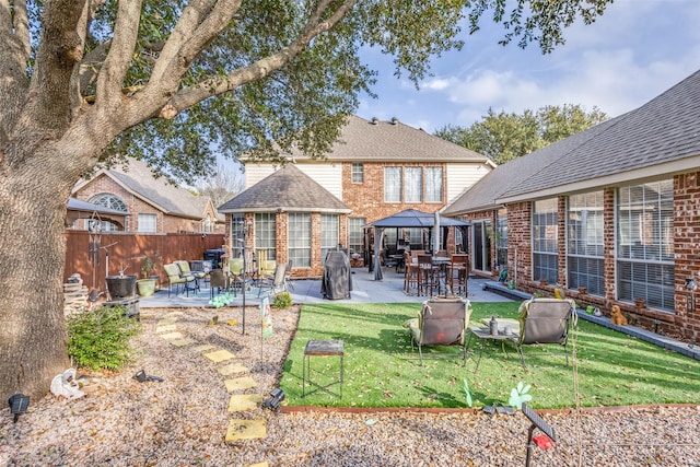 back of house with a gazebo, fence, an outdoor structure, a patio area, and brick siding