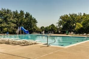 pool featuring a water slide and a patio area