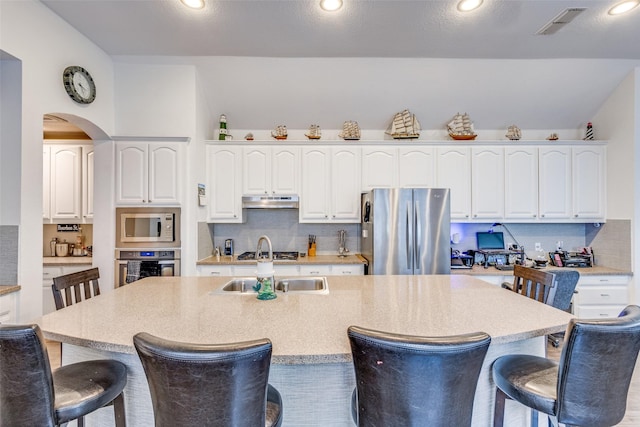 kitchen featuring stainless steel appliances, a breakfast bar, white cabinetry, and backsplash