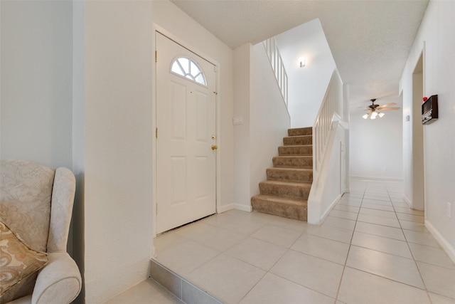 foyer with ceiling fan, light tile patterned floors, and a textured ceiling