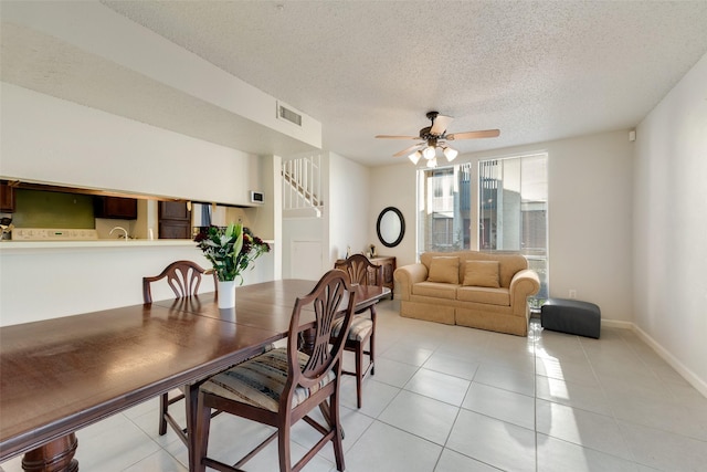 dining area with ceiling fan, light tile patterned floors, and a textured ceiling