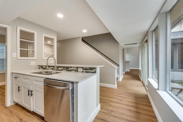 kitchen featuring sink, white cabinets, stainless steel dishwasher, and light wood-type flooring