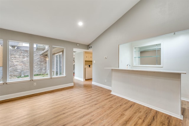 unfurnished living room with lofted ceiling and light wood-type flooring