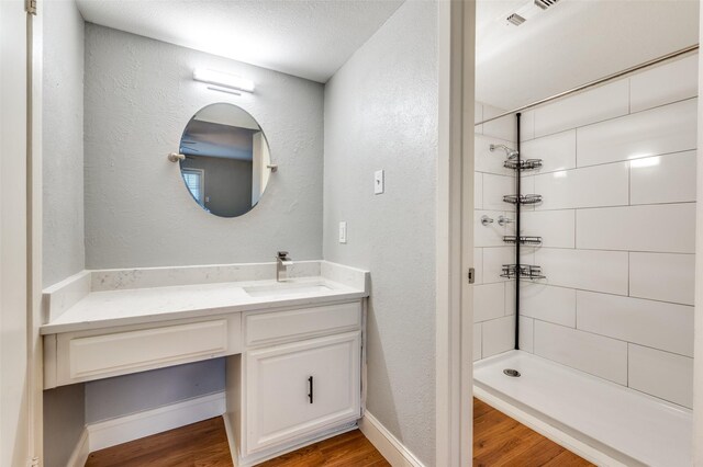 bathroom featuring hardwood / wood-style flooring, vanity, a tile shower, and a textured ceiling