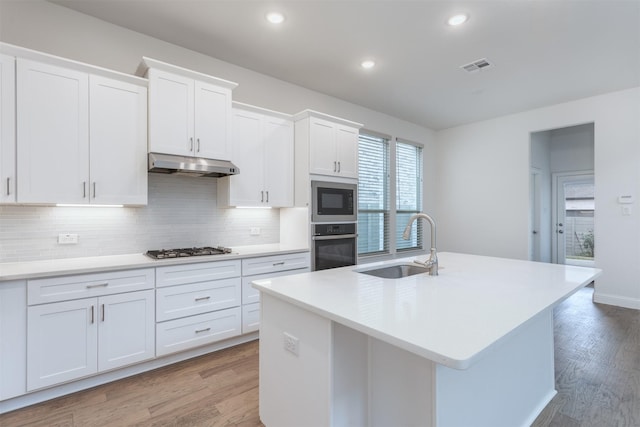 kitchen with appliances with stainless steel finishes, sink, a center island with sink, and white cabinets