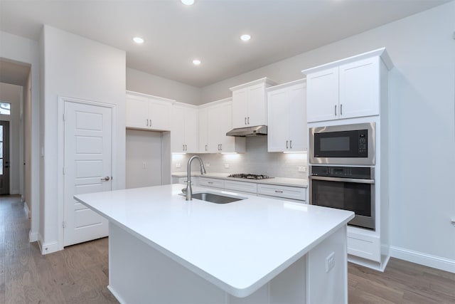 kitchen featuring white cabinetry, stainless steel appliances, a kitchen island with sink, and sink