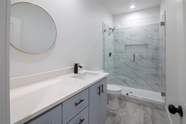 bathroom featuring vanity, a shower with shower door, and toilet