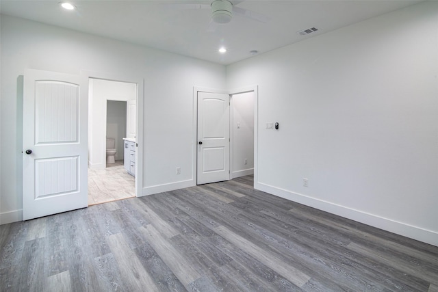 unfurnished bedroom with wood-type flooring, ceiling fan, and ensuite bath