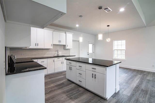 kitchen featuring a kitchen island, decorative light fixtures, tasteful backsplash, white cabinetry, and sink