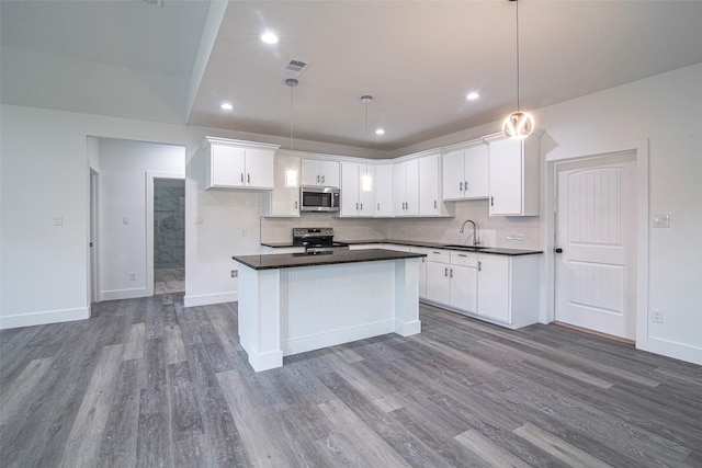 kitchen with a kitchen island, white cabinetry, appliances with stainless steel finishes, and pendant lighting