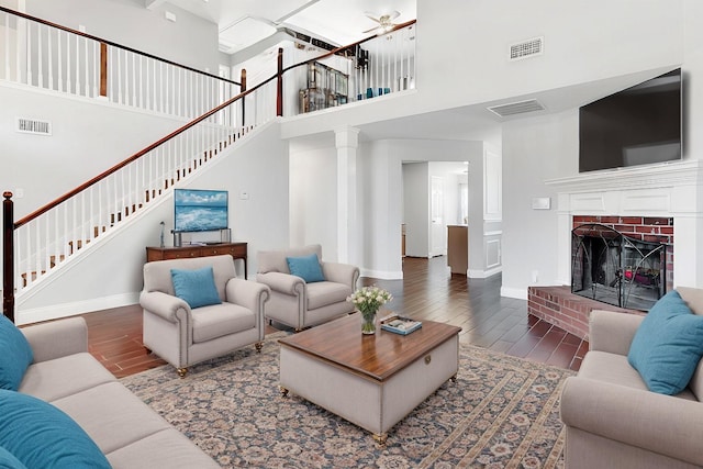 living room with a fireplace, a towering ceiling, and dark hardwood / wood-style floors