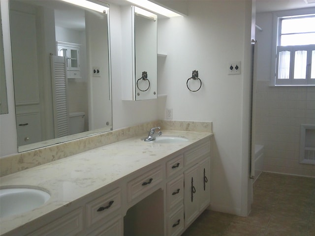 bathroom featuring tile patterned flooring, vanity, and a washtub